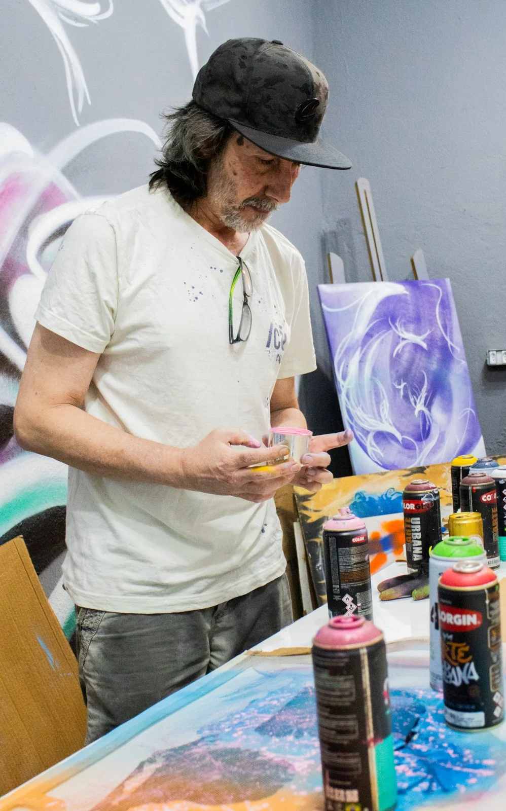 Artista trabalha com pintura, moldes e materiais sobre uma mesa