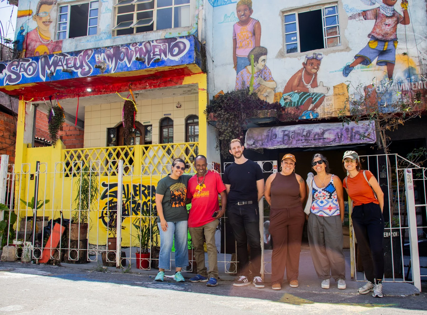 Grupo de visitantes diante de fachada amarela com pinturas