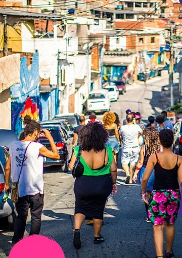 Grupo caminha por rua estreita entre casas e pinturas