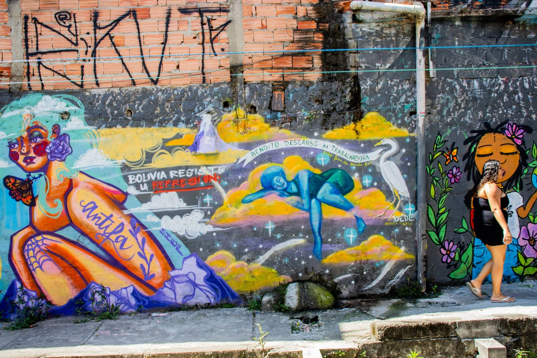 Mural de figuras coloridas ao lado de uma passagem urbana