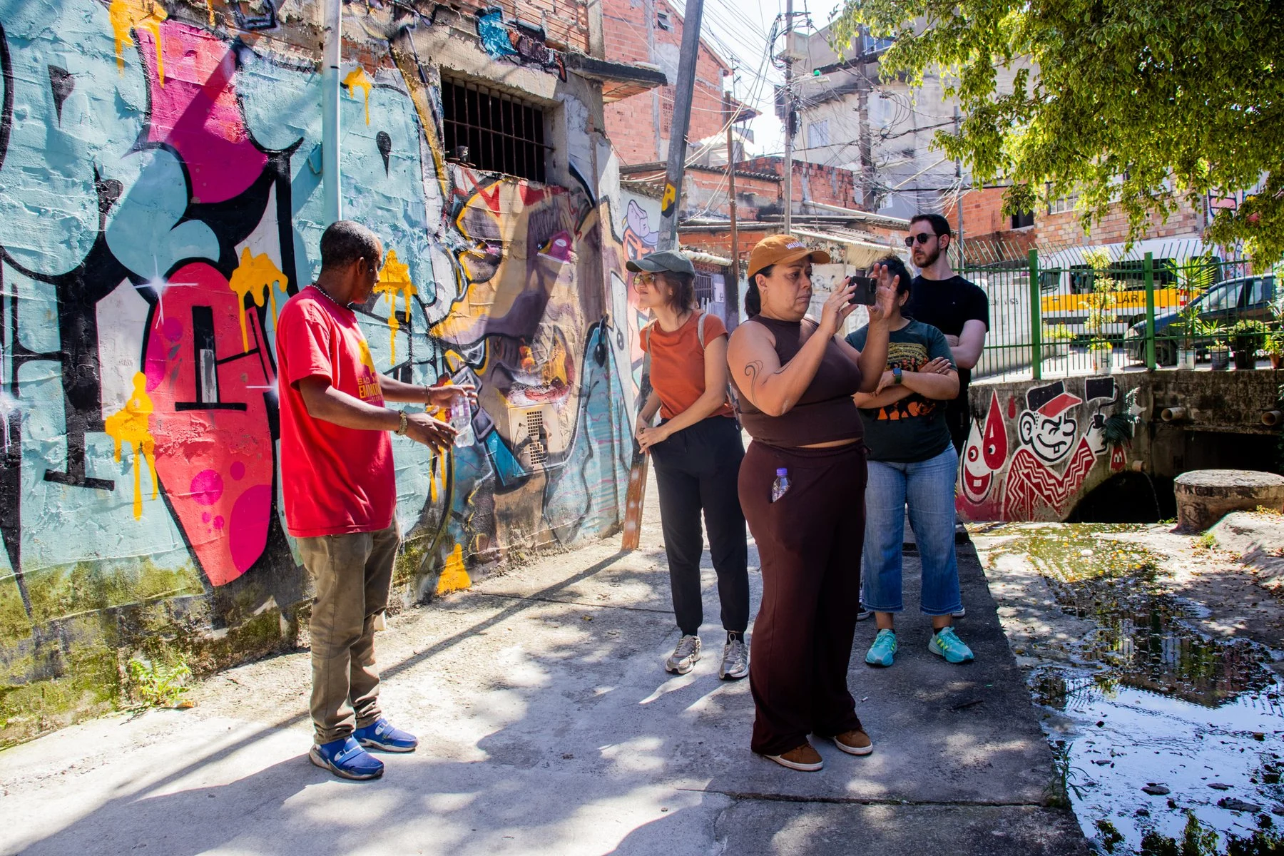 Grupo caminha junto a murais e conversa durante visita